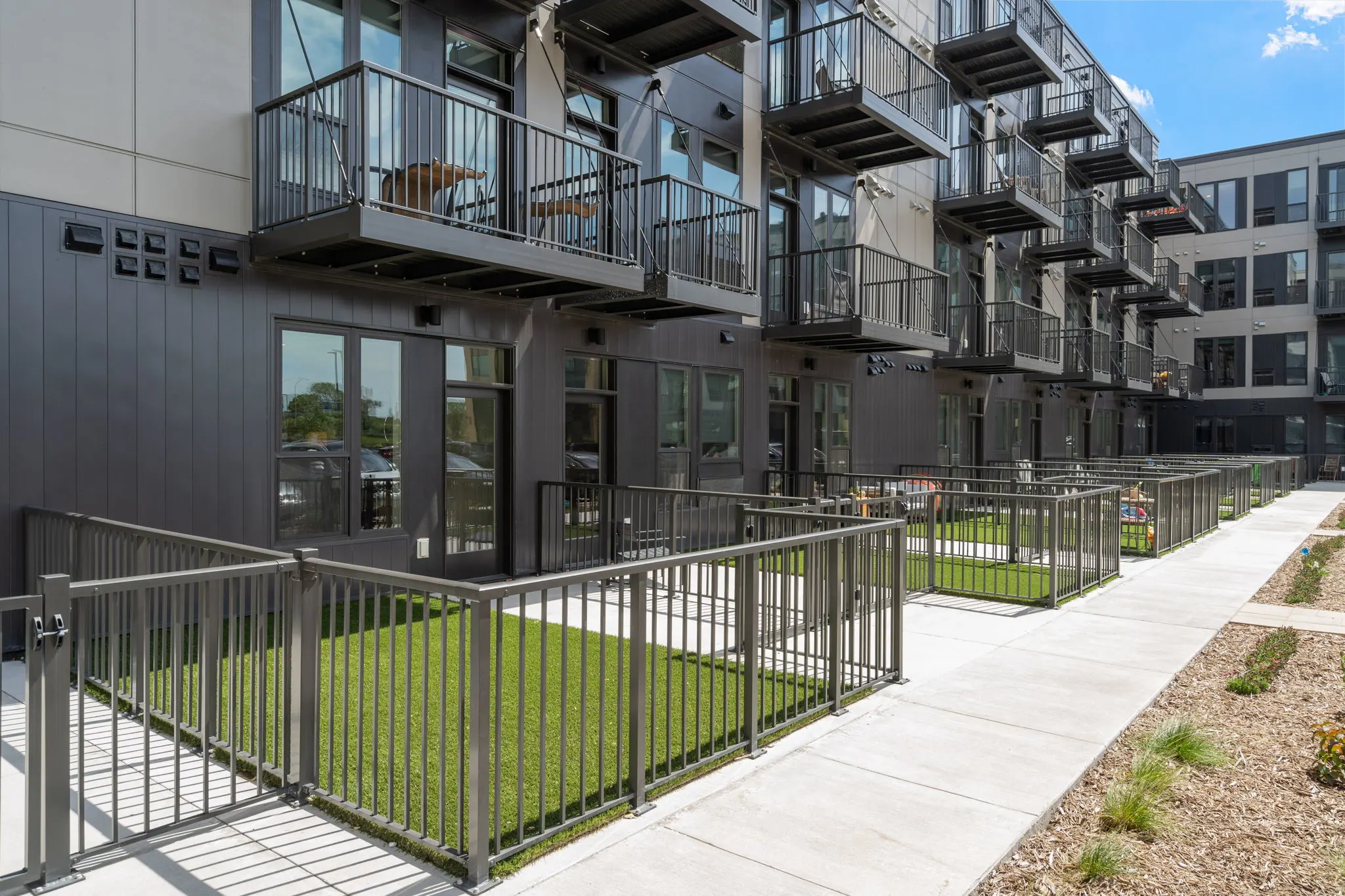 Ground-level private patios at The Townline Apartments with fenced yard areas and upper balconies above.