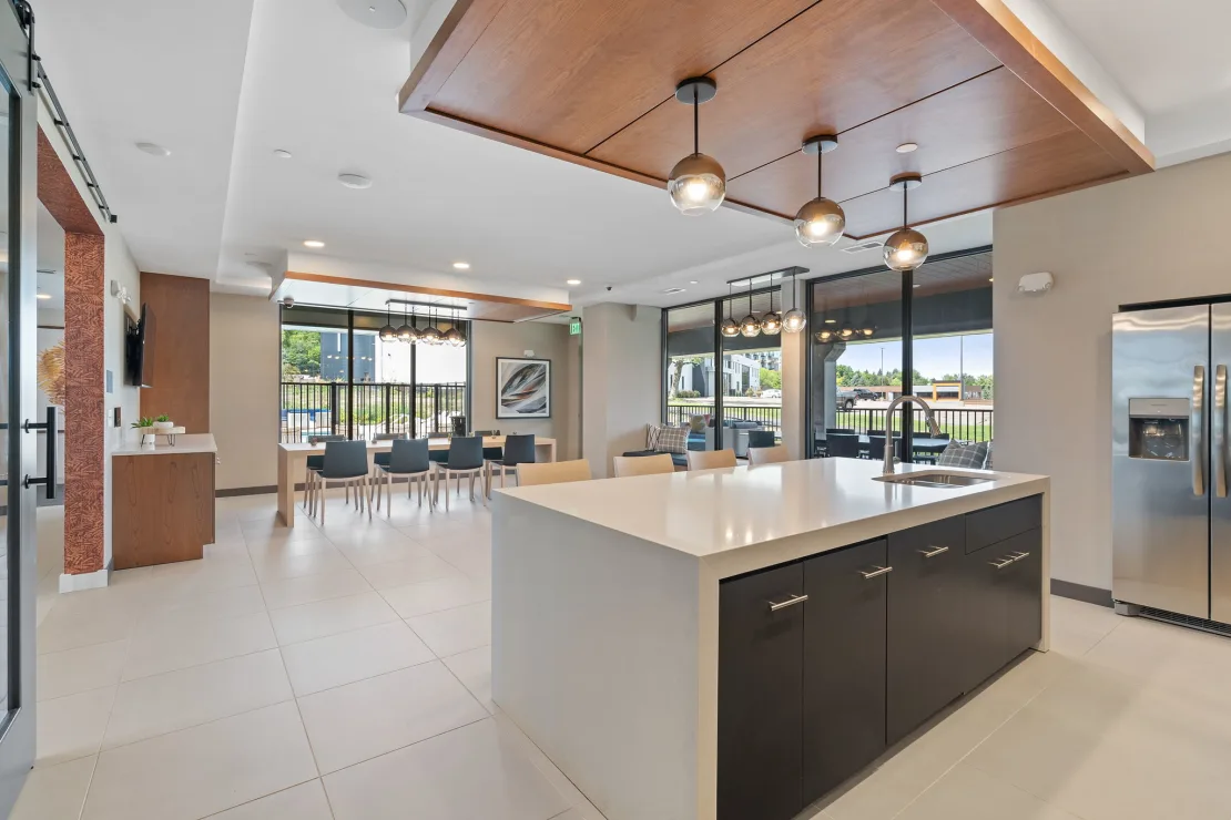 Community kitchen and lounge at The Townline Apartments with oversized island, dining space, and outdoor access.