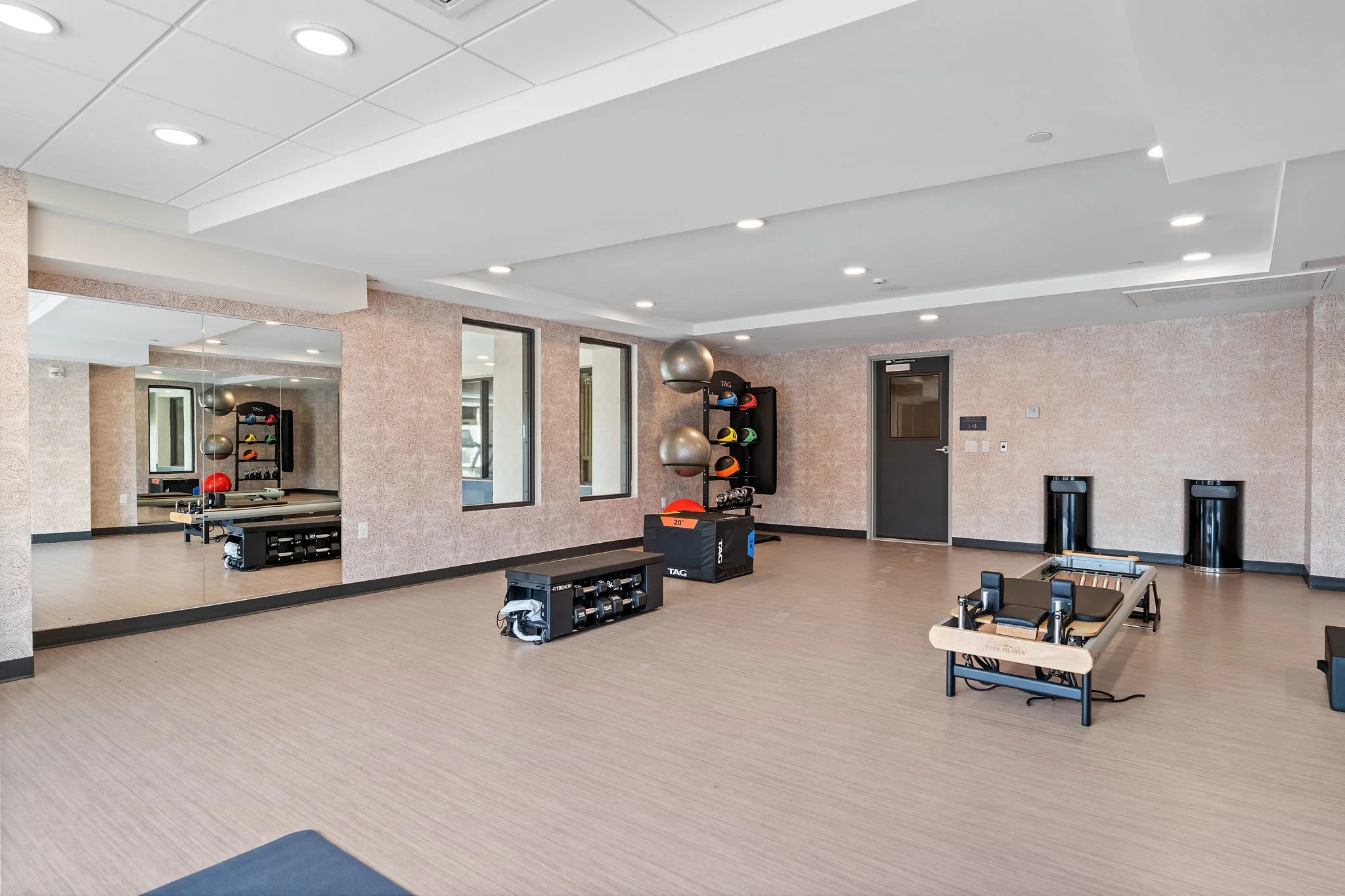 Fitness studio at The Townline Apartments with mirrored walls, reformer machines, open workout space, and training equipment.