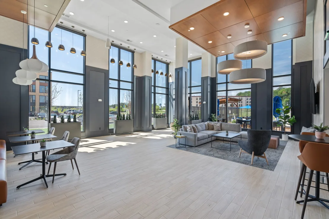 Lobby lounge at The Townline Apartments with double-height windows, modern seating, and natural light.