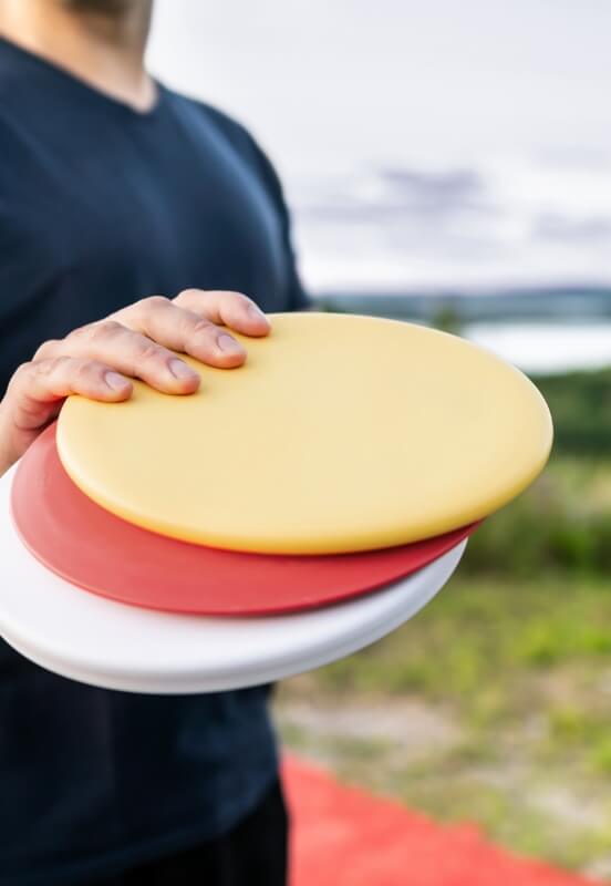 Person holding colorful disc golf discs outdoors