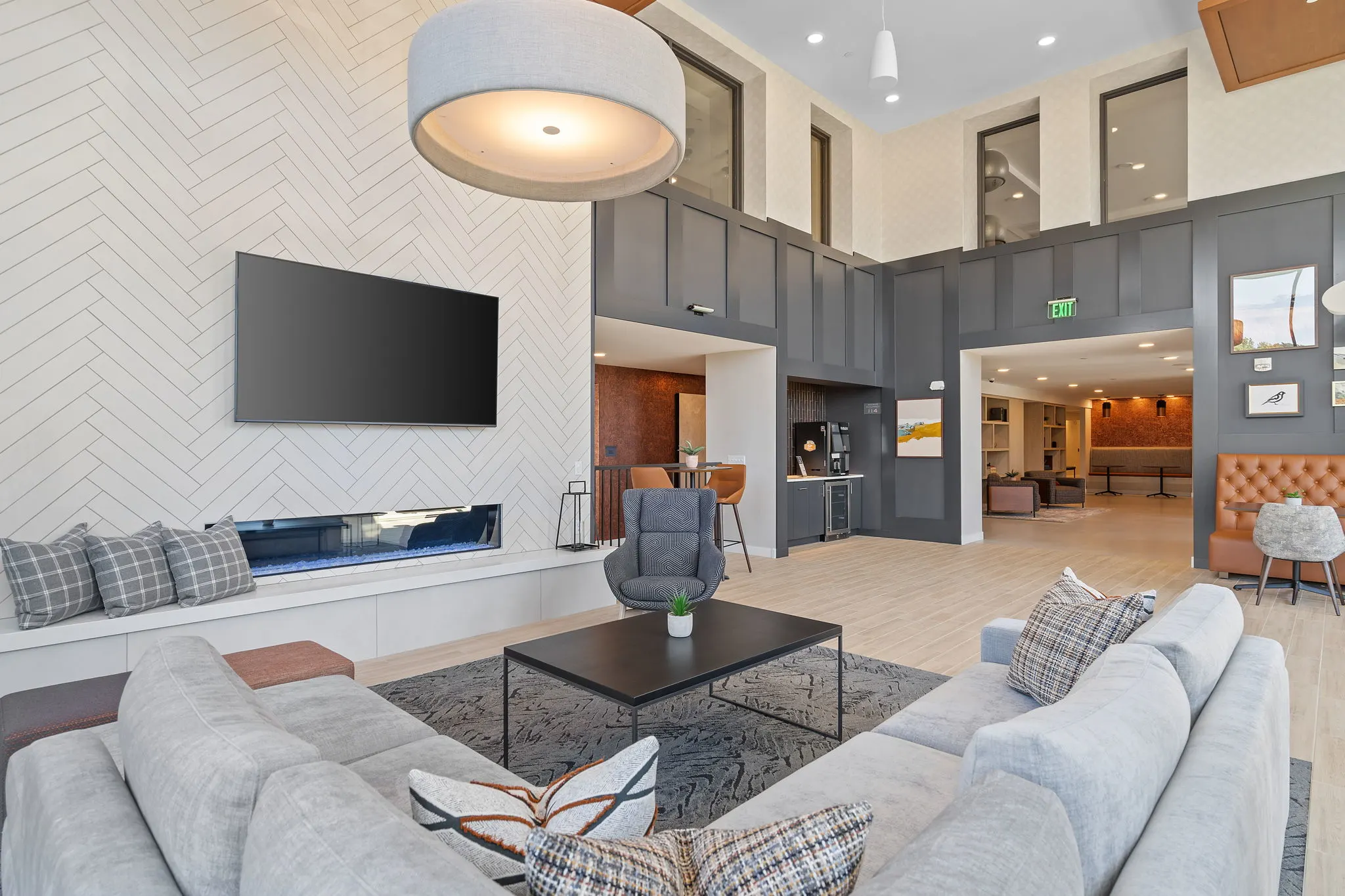 Clubroom lounge at The Townline Apartments with fireplace, TV, soft seating, and adjacent café-style area.