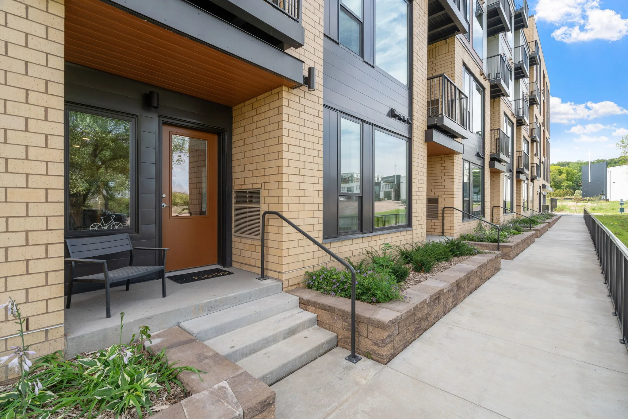 Ground-level private entrance at The Townline Apartments with front steps, patio seating, and landscaped walkway.