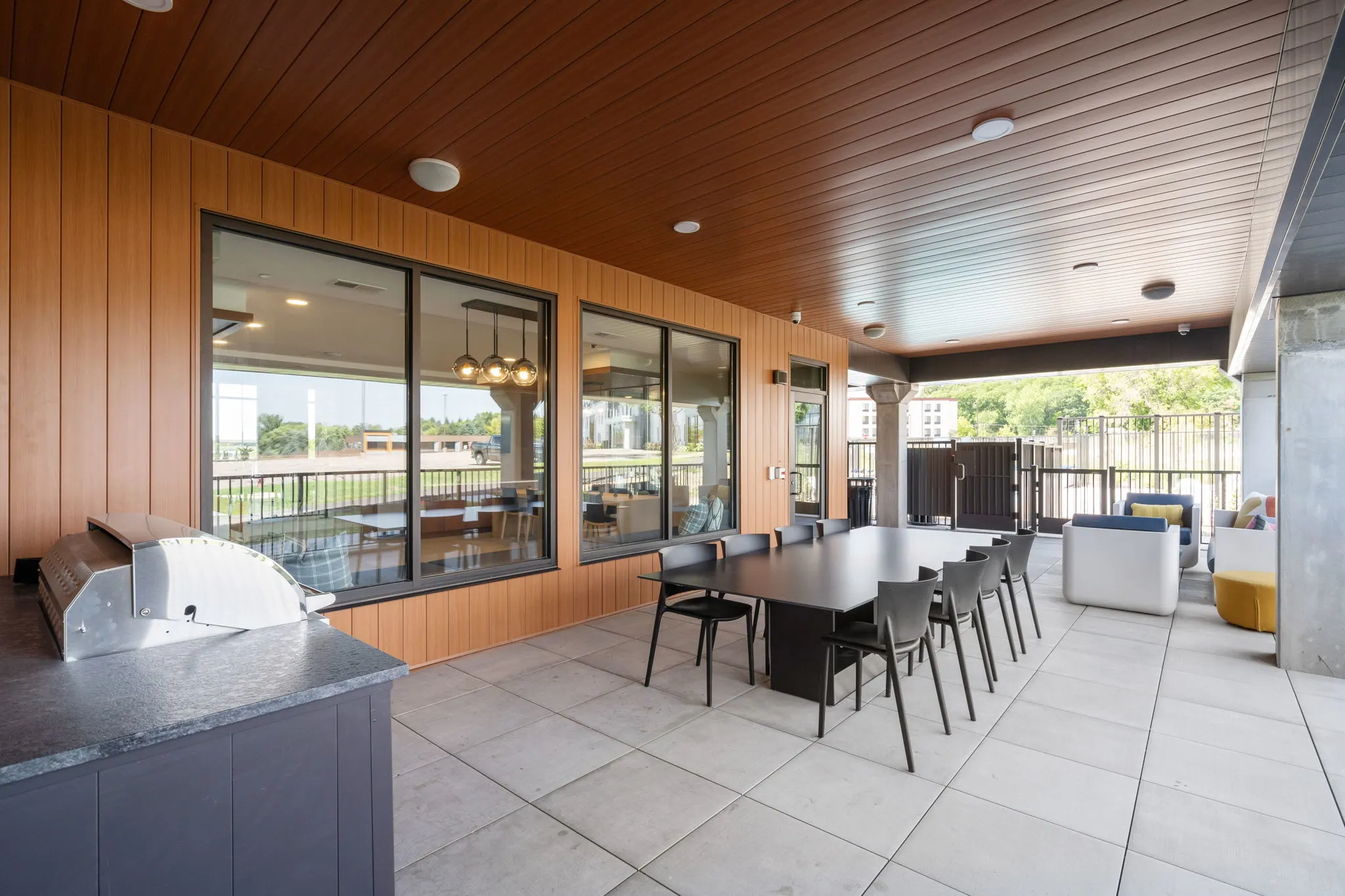 Covered outdoor amenity patio at The Townline Apartments with dining table, grill, and lounge seating.