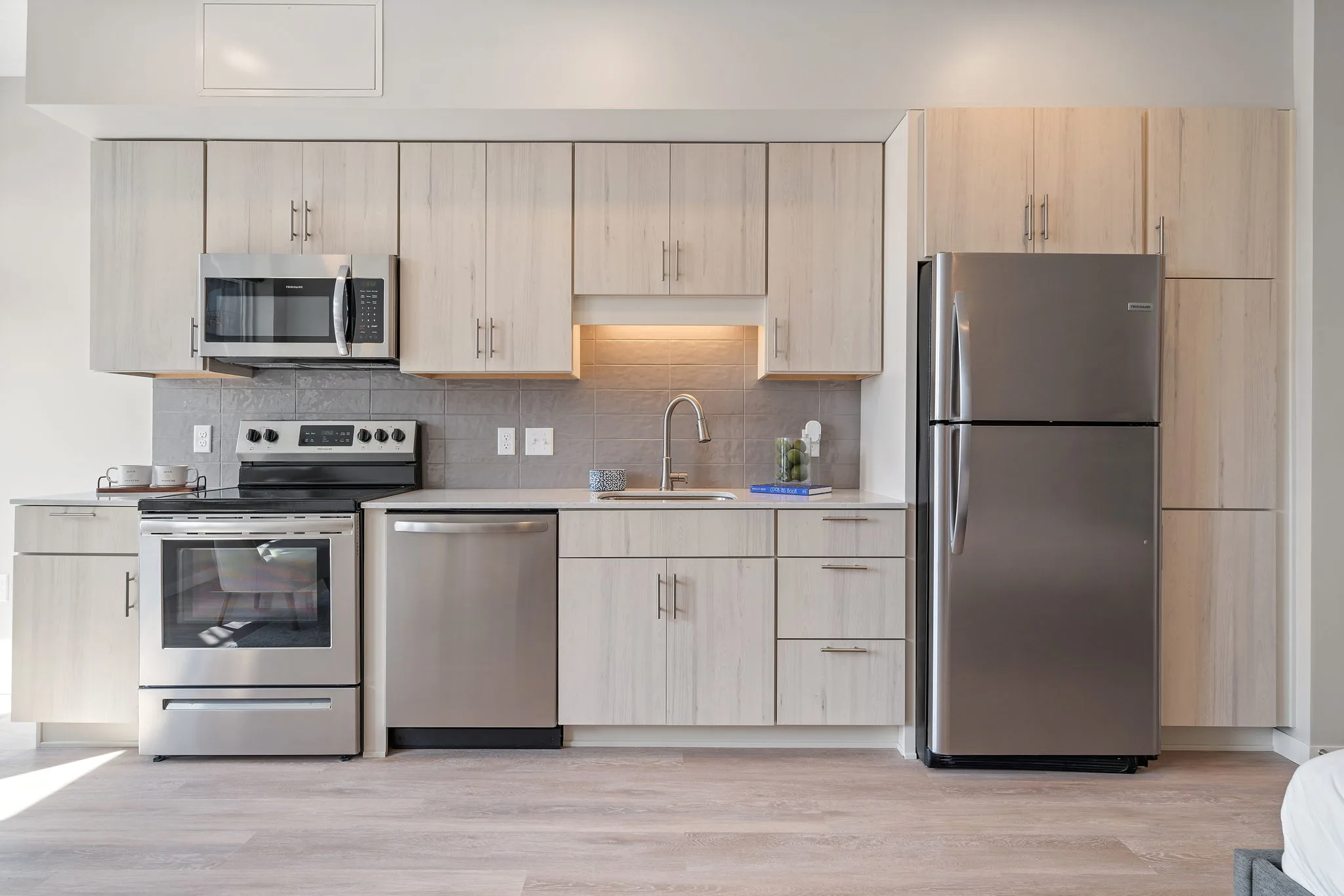 Kitchen at The Townline Apartments with stainless steel appliances, modern cabinetry, and under-cabinet lighting.