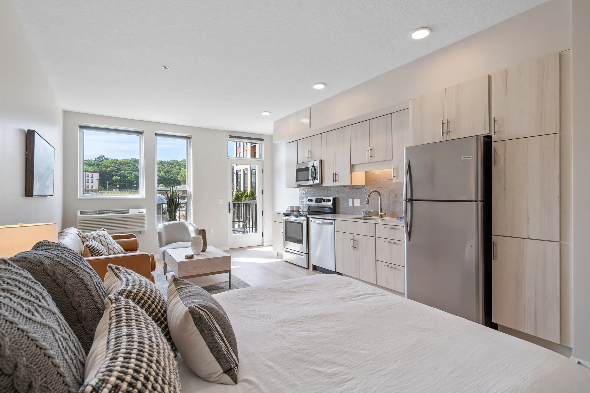 Studio apartment at The Townline Apartments with bed, kitchenette, seating area, and balcony access.