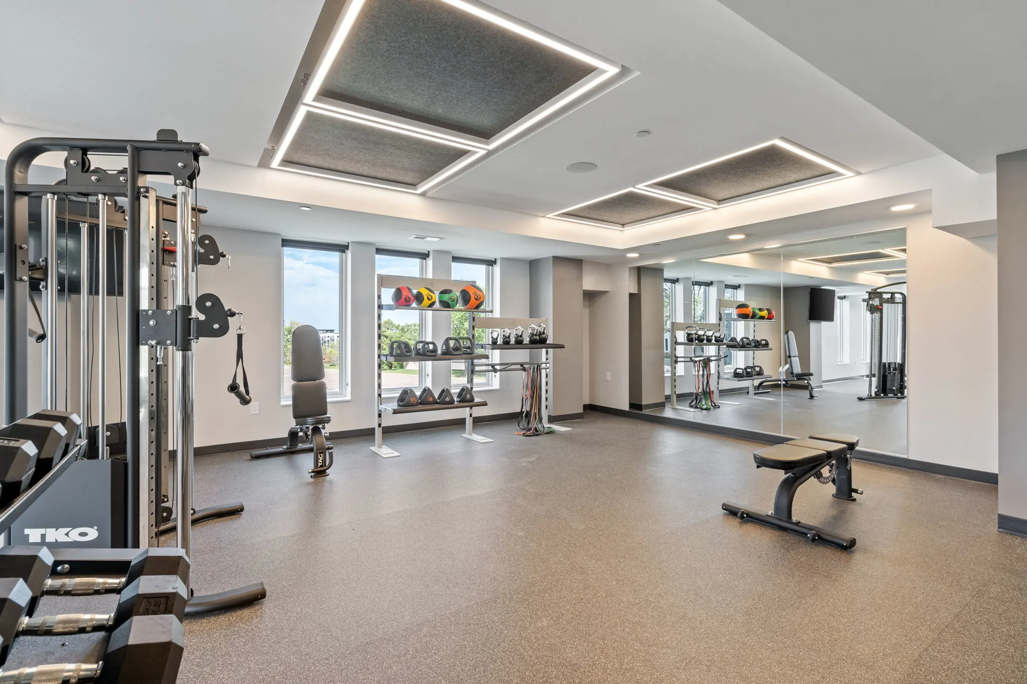 Fitness center at The Townline Apartments with cable machine, bench, free weights, and mirrored wall.