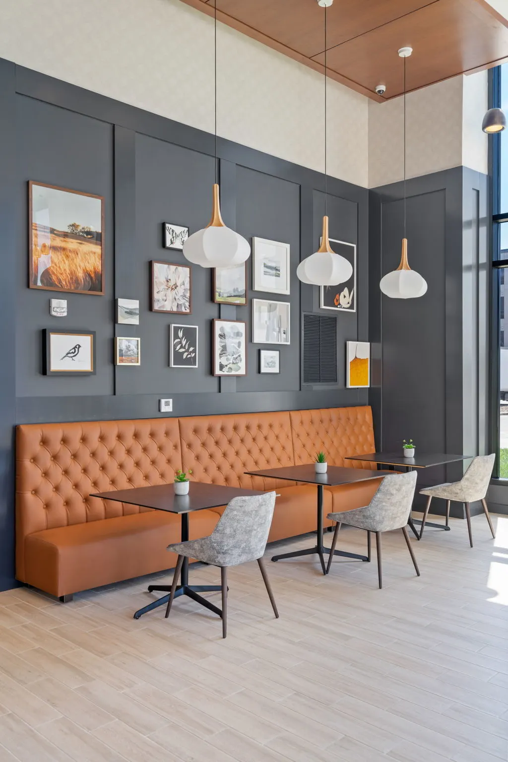 Banquette seating area at The Townline Apartments with café tables, pendant lights, and framed wall art.