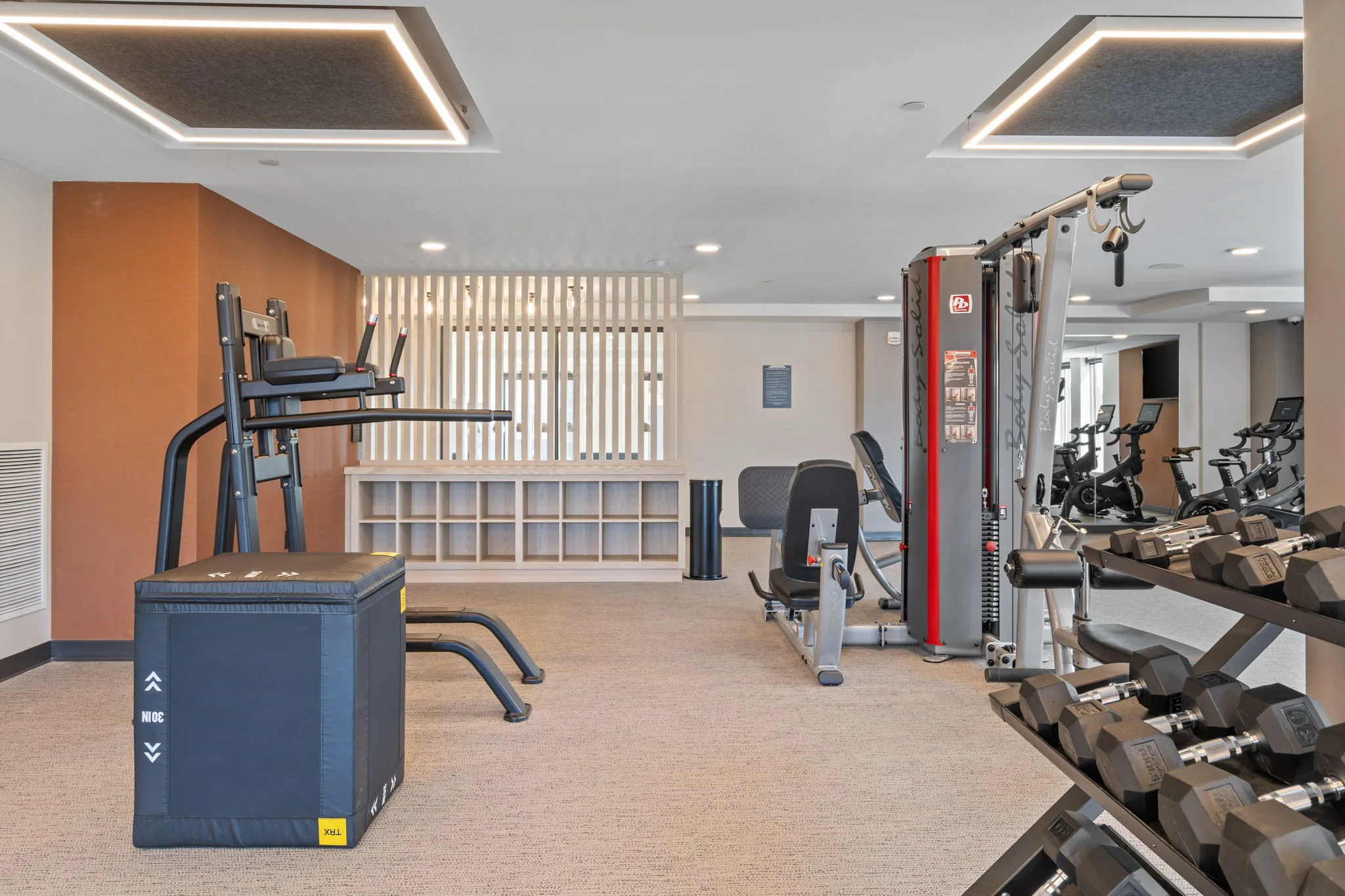 Fitness center at The Townline Apartments with weight equipment, plyo box, dumbbell rack, and cycling bikes.