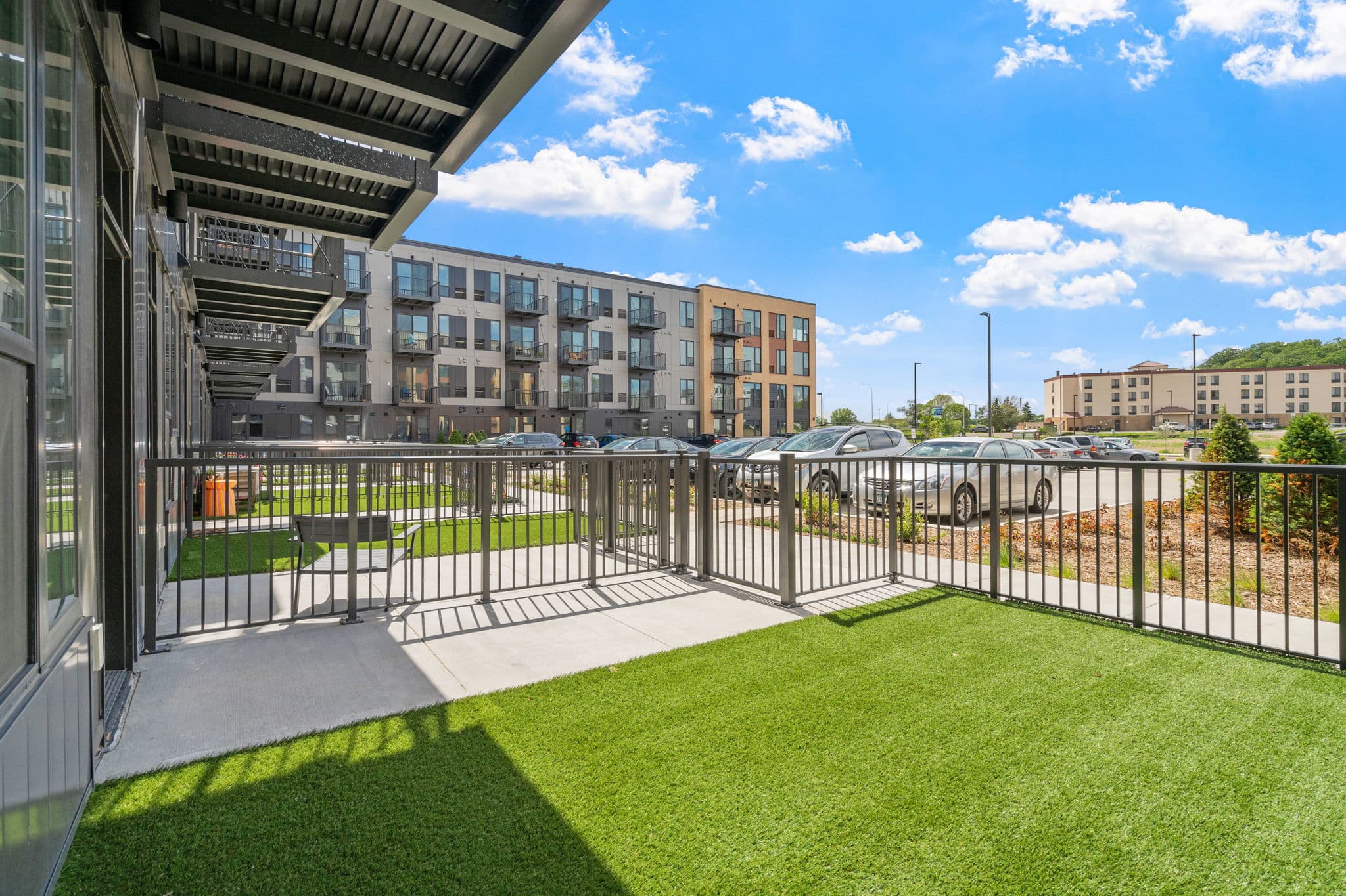 Ground-level private patio at The Townline Apartments with fenced yard space and views of the community building.