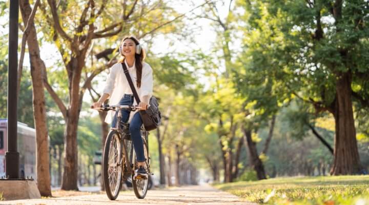 Woman riding a bicycle along a sunlit tree-lined path