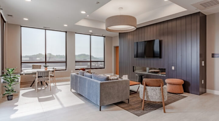 Clubroom lounge at The Townline Apartments with fireplace, TV, seating area, and large windows.