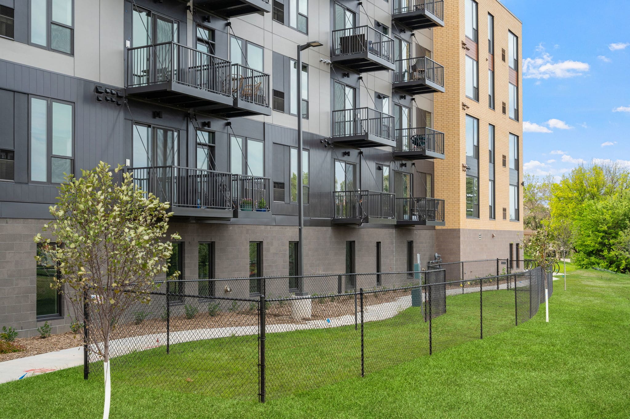 Side view of The Townline Apartments showing balconies, lower-level patios, and landscaped lawn.