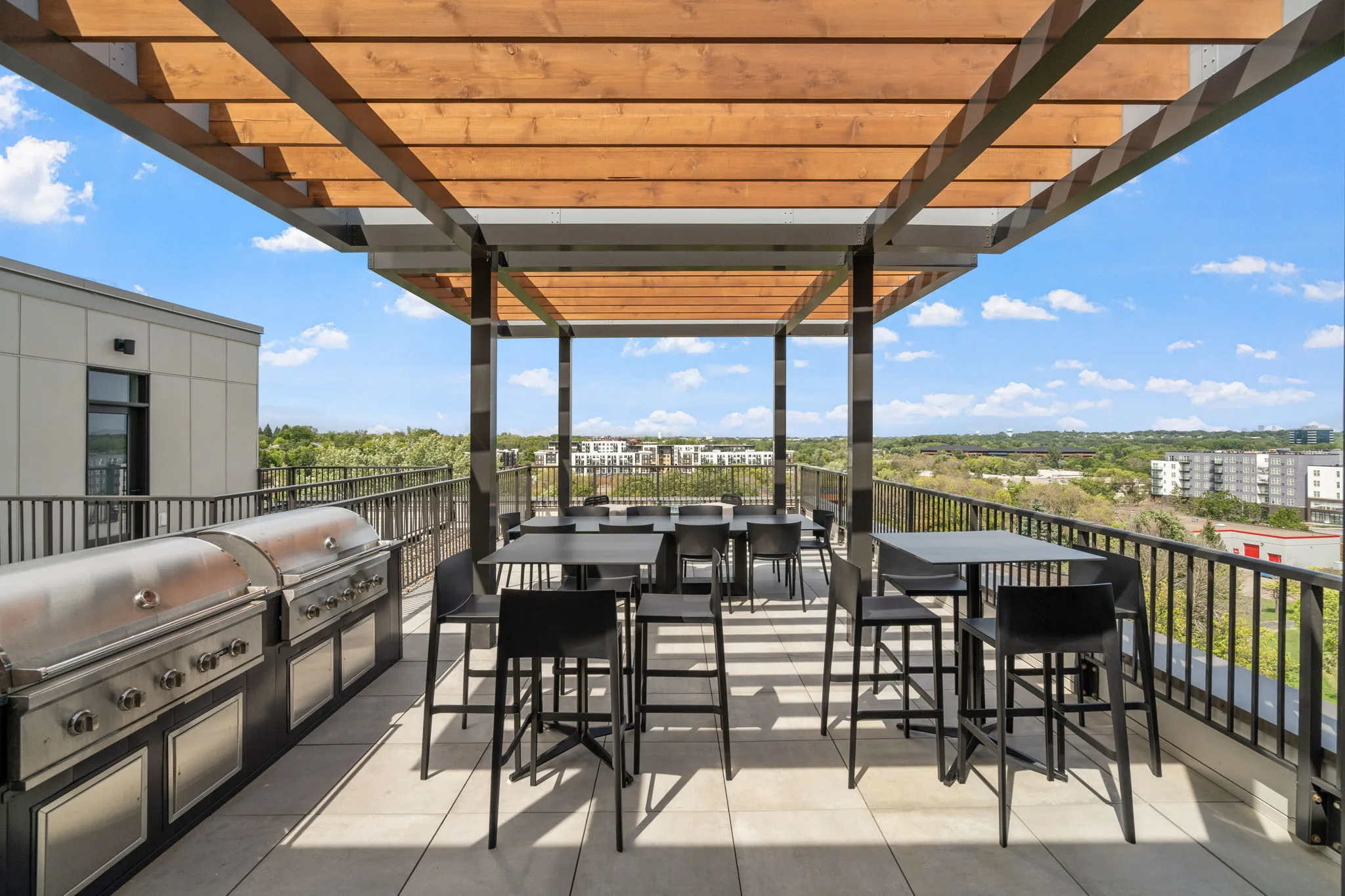 Rooftop patio at The Townline Apartments with pergola-covered dining area, built-in grills, and open views.
